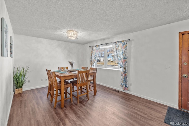 dining room with a textured ceiling, dark wood-type flooring, visible vents, and baseboards