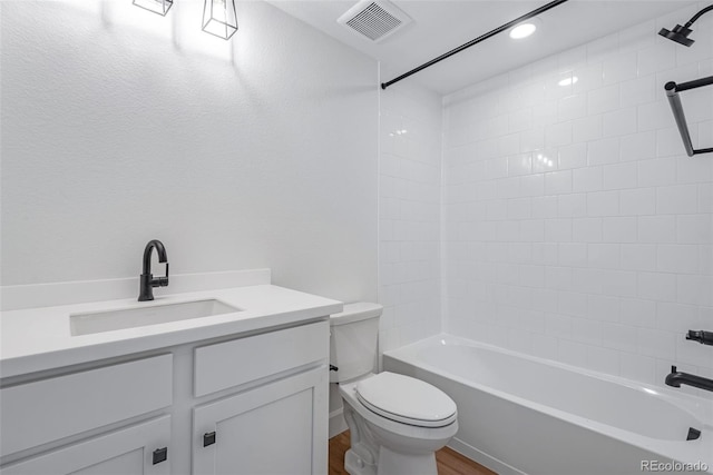 full bathroom featuring hardwood / wood-style floors, vanity, tiled shower / bath combo, and toilet