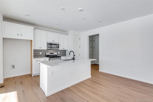 kitchen featuring white cabinets, stainless steel appliances, a center island with sink, and sink