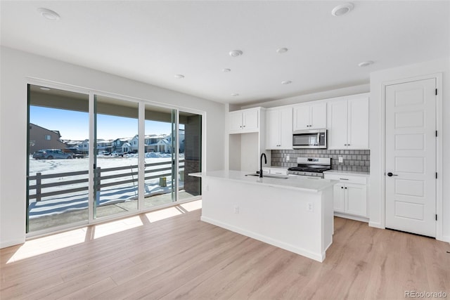 kitchen featuring sink, light hardwood / wood-style floors, a center island with sink, white cabinets, and appliances with stainless steel finishes