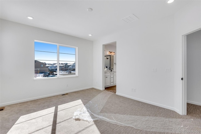 bedroom featuring ensuite bath and light colored carpet