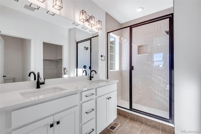 bathroom featuring tile patterned flooring, vanity, toilet, and a shower with shower door