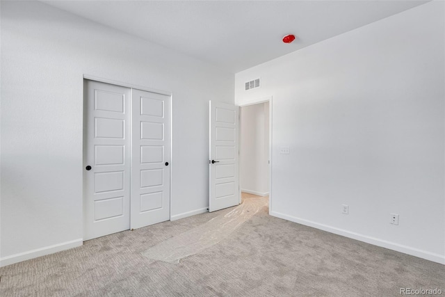 unfurnished bedroom featuring a closet and light colored carpet