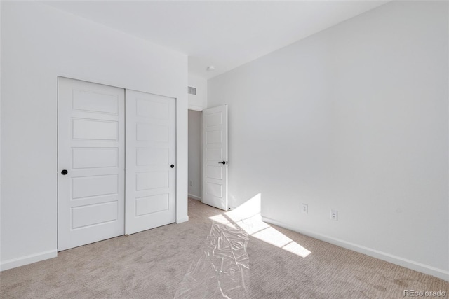 unfurnished bedroom featuring light carpet and a closet