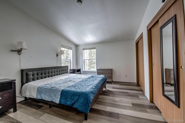 492 Kimmes Ln, Breckenridge, CO 80424 - bedroom featuring light wood-style floors, vaulted ceiling, and a textured ceiling