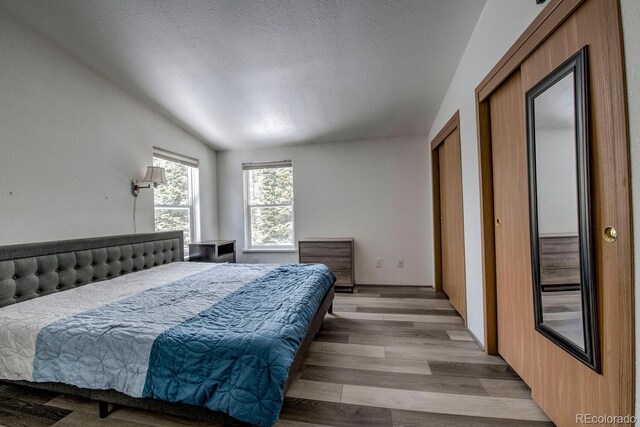 492 Kimmes Ln, Breckenridge, CO 80424 - bedroom featuring light wood finished floors, lofted ceiling, and a textured ceiling