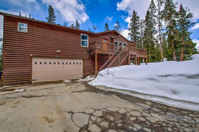 492 Kimmes Ln, Breckenridge, CO 80424 - snow covered rear of property featuring an attached garage, log veneer siding, driveway, and a wooden deck