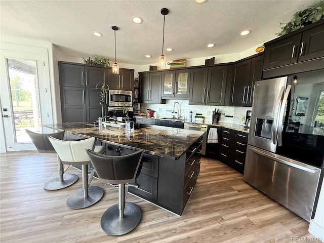 653 Glenarbor Cir, Longmont, CO 80504 - kitchen featuring stainless steel appliances, a sink, a breakfast bar, dark stone counters, and tasteful backsplash