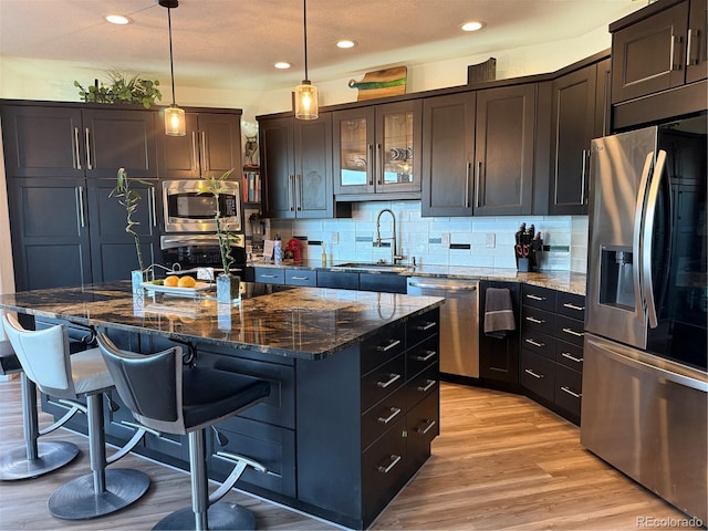 653 Glenarbor Cir, Longmont, CO 80504 - kitchen featuring appliances with stainless steel finishes, a sink, a center island with sink, light wood finished floors, and tasteful backsplash