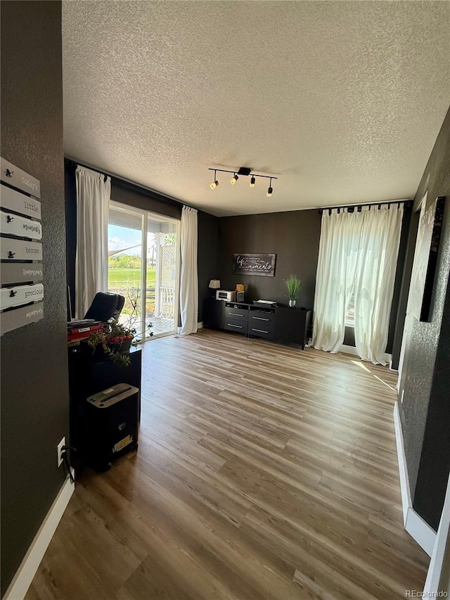653 Glenarbor Cir, Longmont, CO 80504 - living area with a textured ceiling, wood finished floors, rail lighting, and baseboards