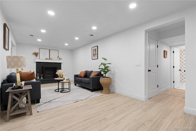 living room featuring a brick fireplace and light hardwood / wood-style flooring