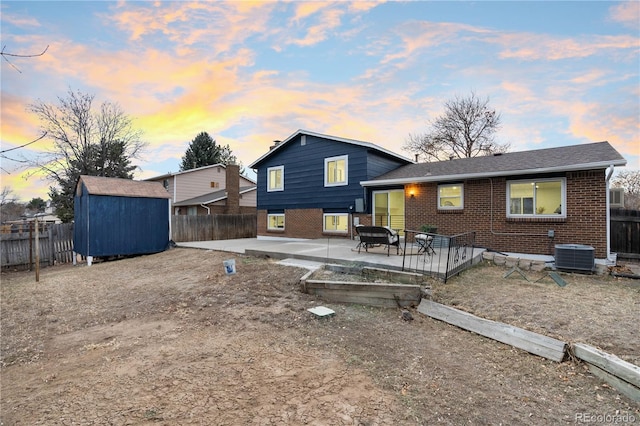 back house at dusk featuring cooling unit, a patio, a shed, and a deck