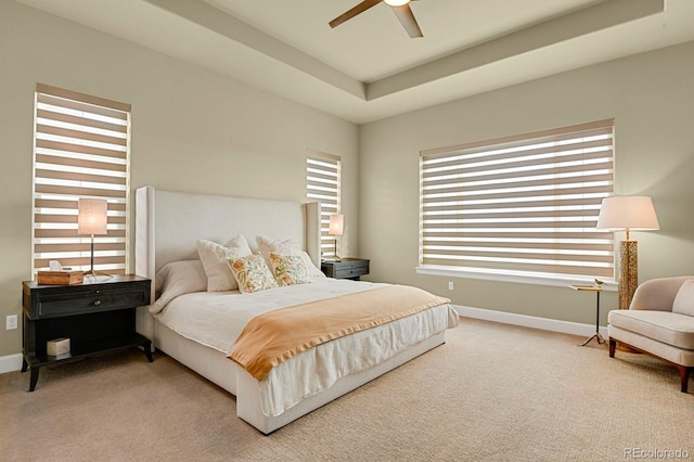 carpeted bedroom featuring ceiling fan and a tray ceiling