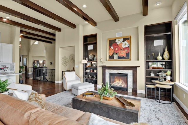 living room featuring wood-type flooring, a fireplace, beam ceiling, and a wealth of natural light