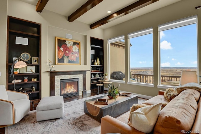 living room featuring built in shelves, a stone fireplace, and plenty of natural light