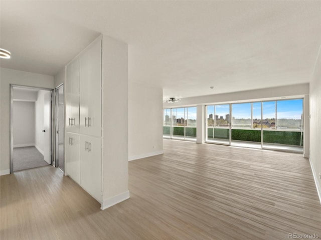 unfurnished living room with baseboards and light wood finished floors
