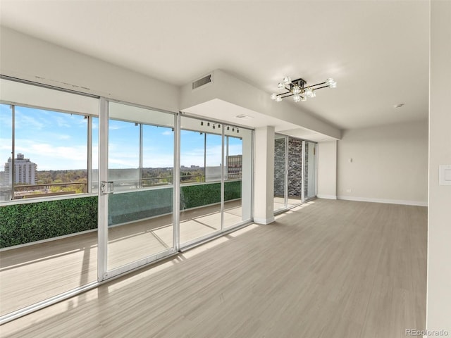 unfurnished living room featuring baseboards, plenty of natural light, wood finished floors, and a chandelier