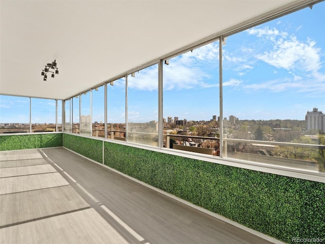 unfurnished sunroom with a view of city and wood finished floors