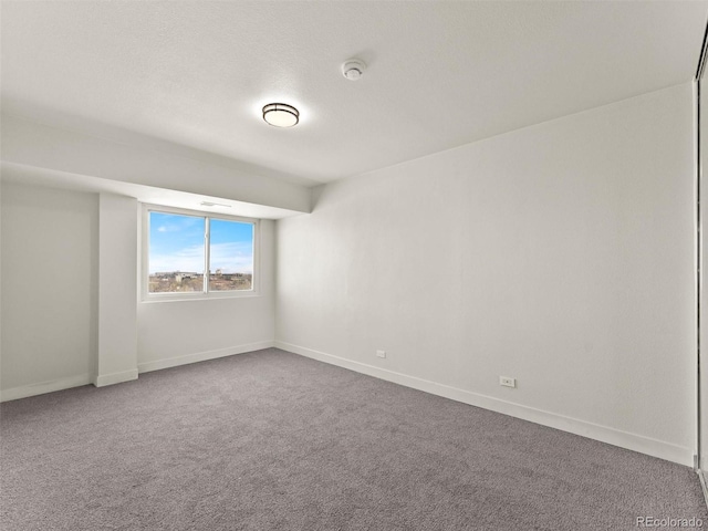unfurnished room featuring dark colored carpet and baseboards