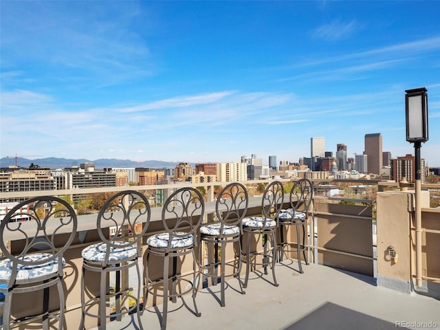 view of patio featuring a view of city, a mountain view, and a balcony