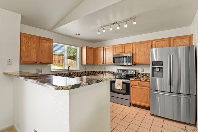 kitchen featuring kitchen peninsula, stainless steel appliances, vaulted ceiling, sink, and light tile patterned floors