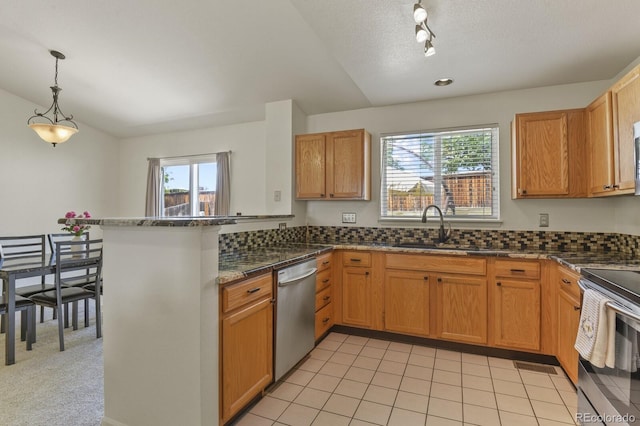 kitchen featuring sink, stainless steel appliances, kitchen peninsula, dark stone counters, and decorative light fixtures