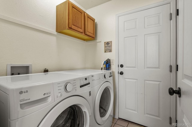 washroom featuring cabinets, light tile patterned floors, and washing machine and dryer