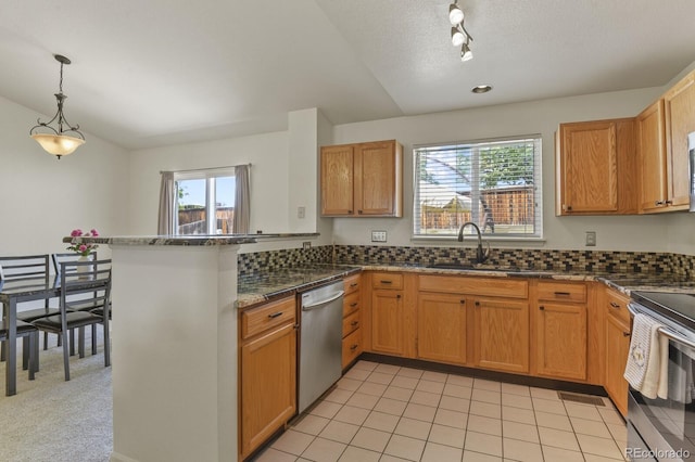 kitchen featuring a peninsula, a sink, decorative light fixtures, rail lighting, and appliances with stainless steel finishes