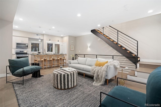 living room with stairway, visible vents, baseboards, and recessed lighting