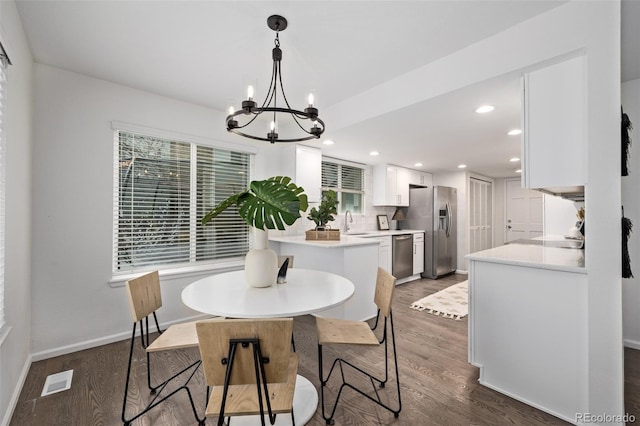 dining space featuring dark wood-type flooring, sink, and a notable chandelier