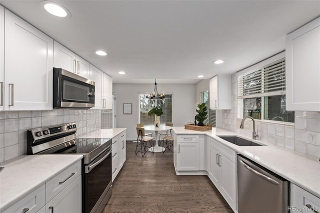 kitchen featuring dark wood-type flooring, sink, decorative light fixtures, appliances with stainless steel finishes, and white cabinets