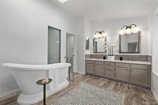 bathroom with vanity, decorative backsplash, wood-type flooring, and a tub