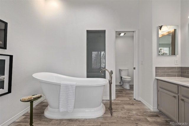 bathroom with vanity, a tub to relax in, wood-type flooring, and toilet