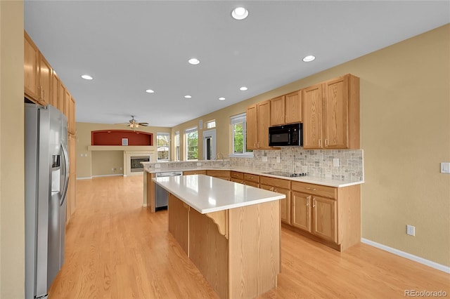 3590 S Malaya St, Aurora, CO 80013 - kitchen featuring black appliances, a sink, a peninsula, light wood-style flooring, and a fireplace