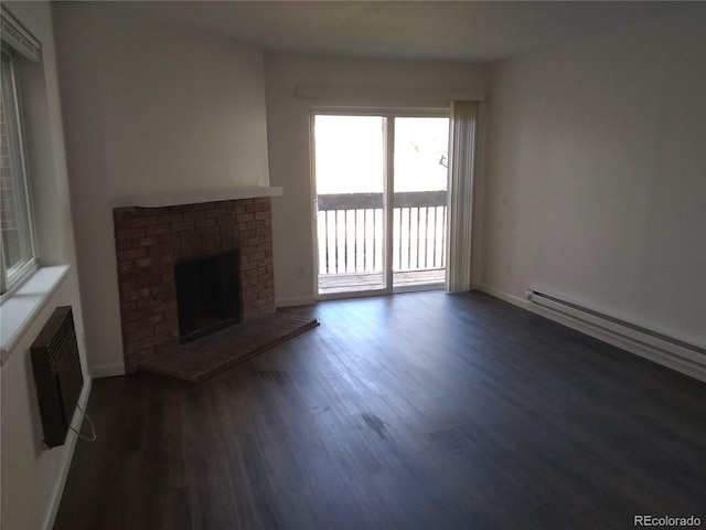 unfurnished living room with dark wood-style floors, a brick fireplace, a baseboard heating unit, and baseboards