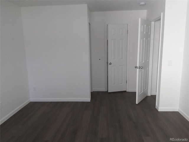 unfurnished room featuring dark wood finished floors, baseboards, and a smoke detector
