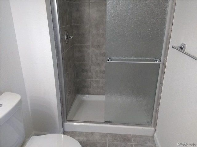 bathroom featuring toilet, a stall shower, and tile patterned floors