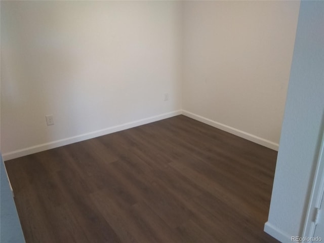 unfurnished room with dark wood-type flooring and baseboards