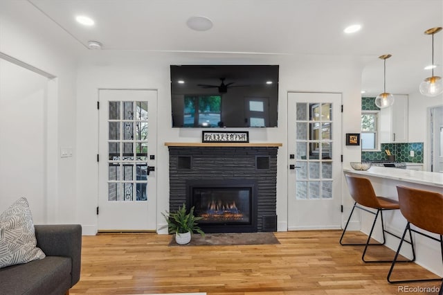 living area with light wood-style flooring, a fireplace with flush hearth, healthy amount of natural light, and recessed lighting