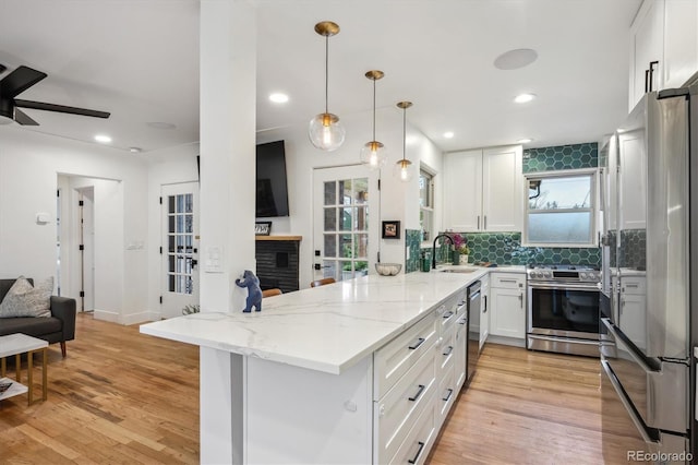 kitchen featuring appliances with stainless steel finishes, a sink, a peninsula, white cabinetry, and recessed lighting