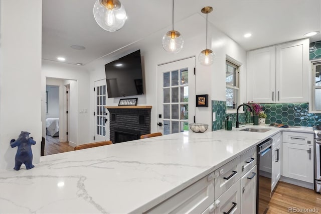 kitchen with dishwasher, a sink, white cabinets, light stone countertops, and plenty of natural light