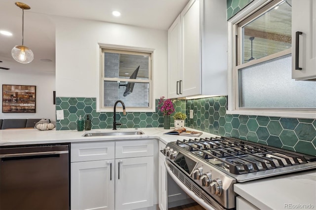 kitchen featuring dishwasher, gas range, a sink, white cabinets, and decorative backsplash