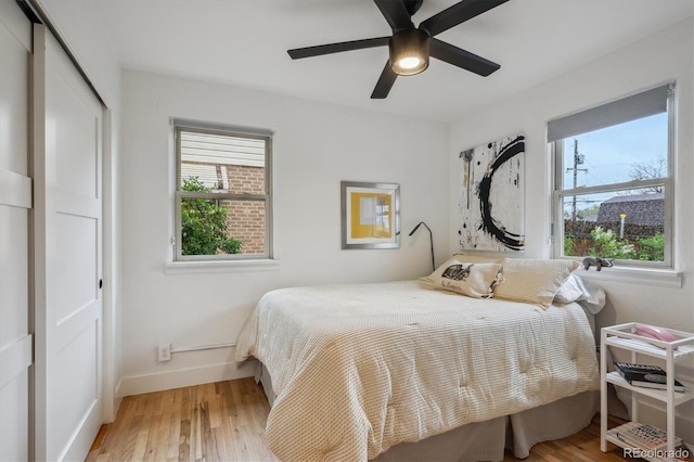 bedroom featuring a closet, wood finished floors, baseboards, and a ceiling fan