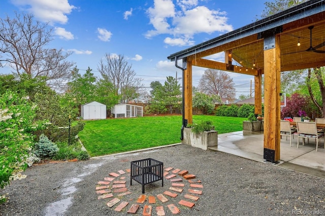 view of patio with a storage shed, an outdoor structure, a fire pit, and ceiling fan