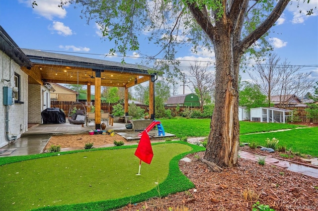 view of yard featuring a patio, a putting green, and an outdoor structure