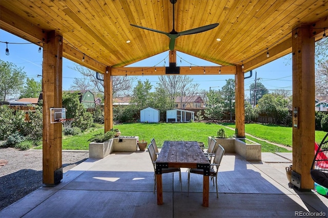 view of patio featuring a storage shed, outdoor dining area, and an outbuilding
