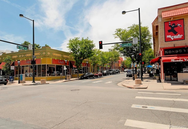view of asphalt road with street lights, sidewalks, traffic lights, and curbs