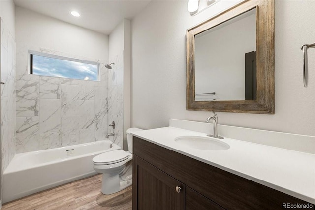 full bathroom with hardwood / wood-style flooring, tiled shower / bath combo, vanity, and toilet