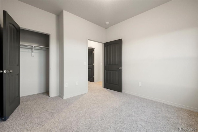 unfurnished bedroom featuring light colored carpet and a closet