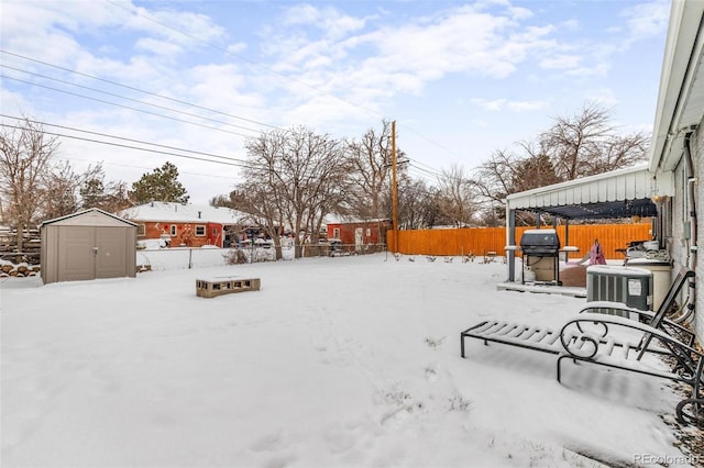 snowy yard featuring a storage unit and central AC unit